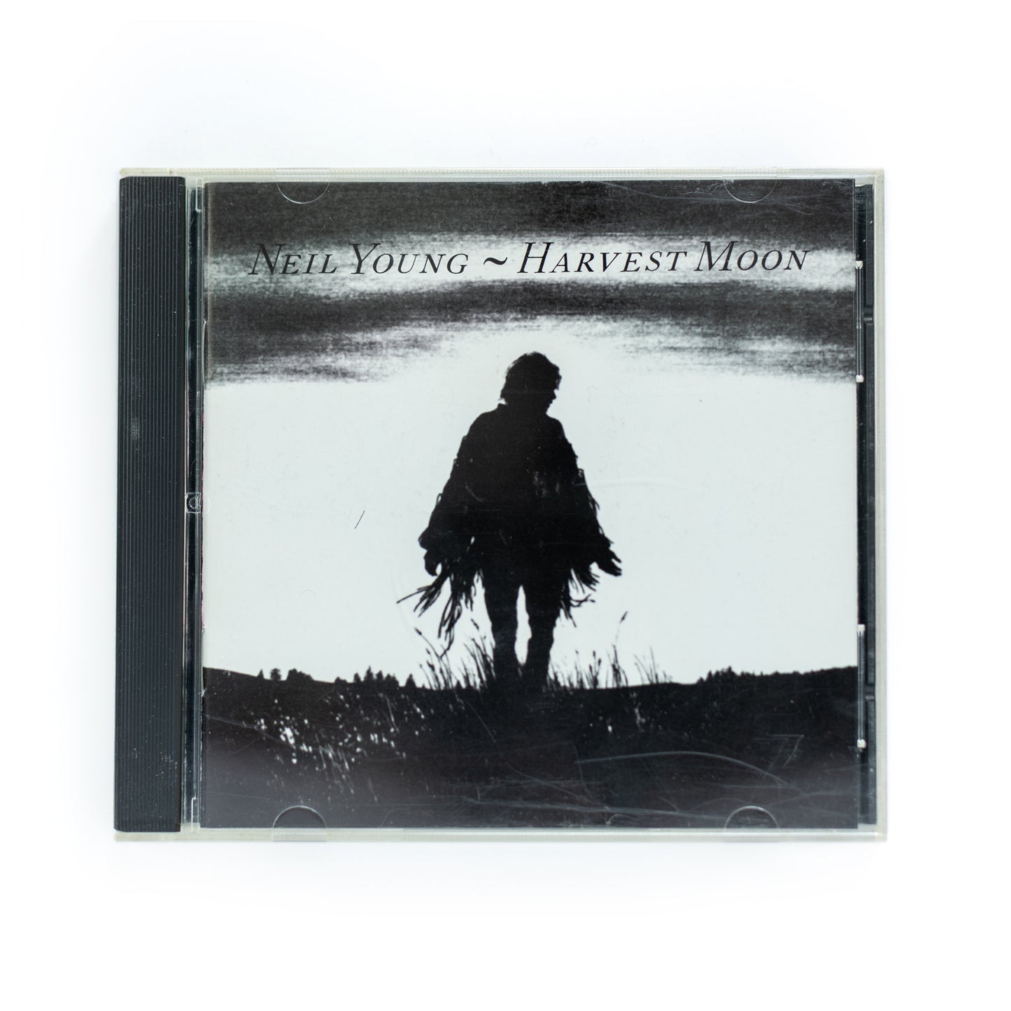 Neil Young – Harvest Moon CD album cover featuring an image of Neil Young against a twilight sky with a large moon in the background, showcasing the rustic and serene vibe of the album's country-folk sound.