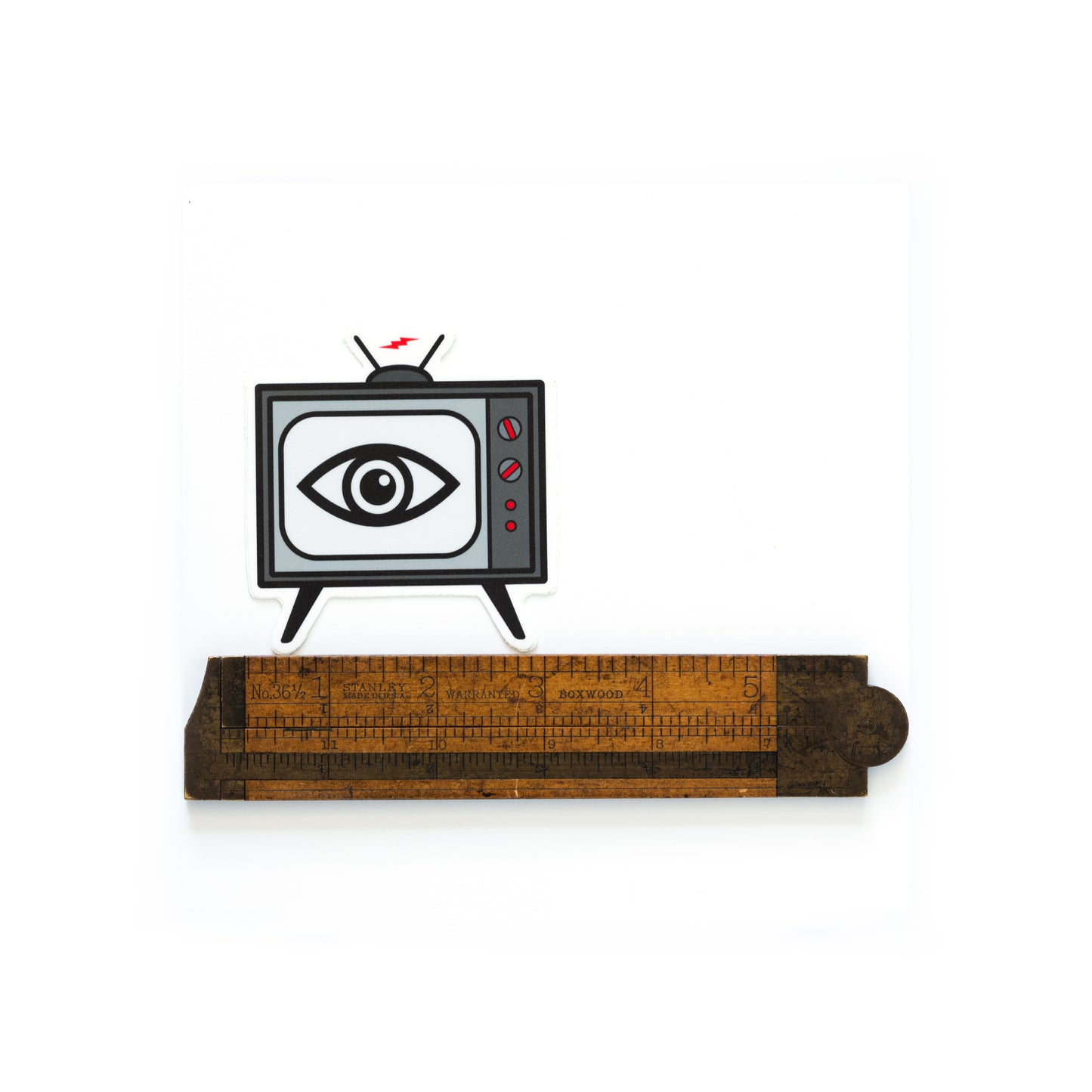 3-inch die cut vinyl sticker with an illustrated vintage TV set and a staring eye on the screen — inspired by The Stooges song “TV Eye” — weatherproof matte finish. Shown with a ruler to show scale.