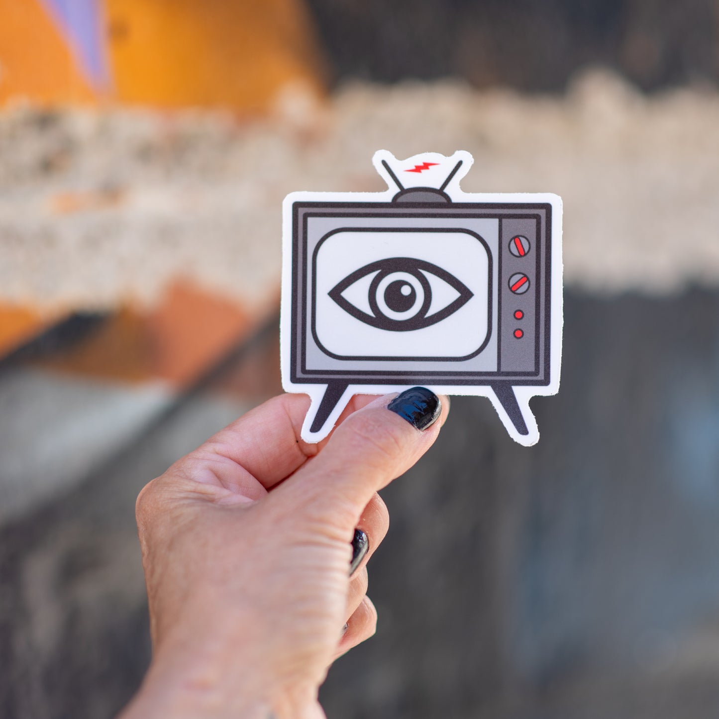 3-inch die cut vinyl sticker with an illustrated vintage TV set and a staring eye on the screen, shot on a textured background — inspired by The Stooges song “TV Eye” — weatherproof matte finish.