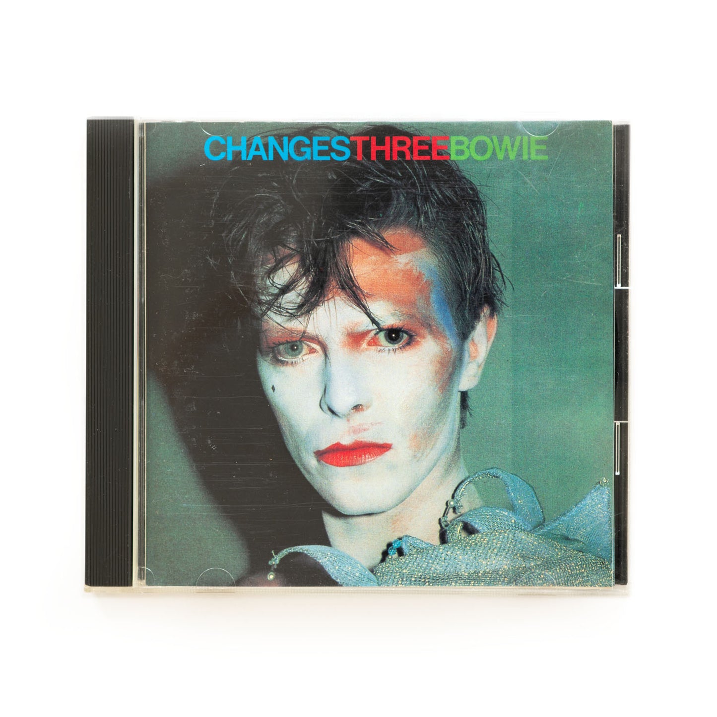 CD cover of David Bowie Changes Three featuring a photograph of the artist with messy makeup on his face.