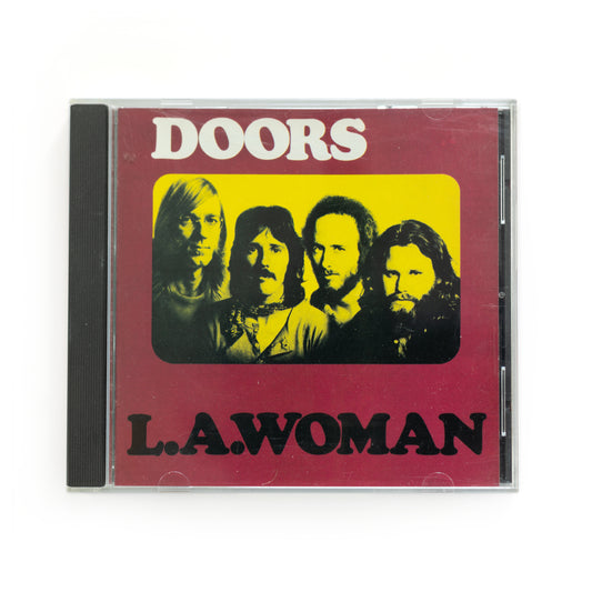 Front cover of The Doors L.A. Woman CD featuring iconic artwork with a portrait of the Doors, 1971 album by legendary rock band The Doors, includes tracks like 'Riders on the Storm,' 'Love Her Madly,' and 'L.A. Woman.'