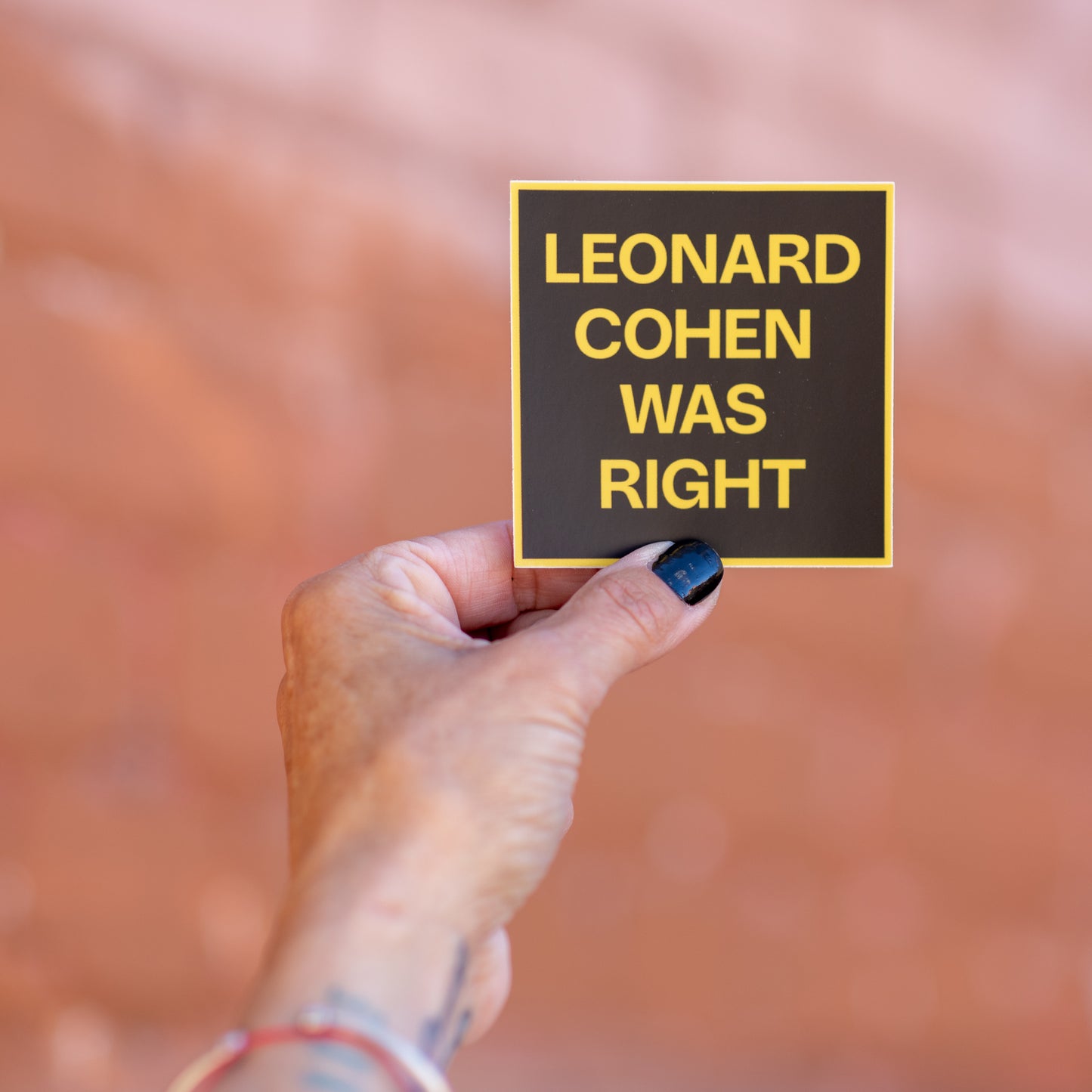 3 inch square Leonard Cohen Was Right sticker. Photographed on a brick backyard.