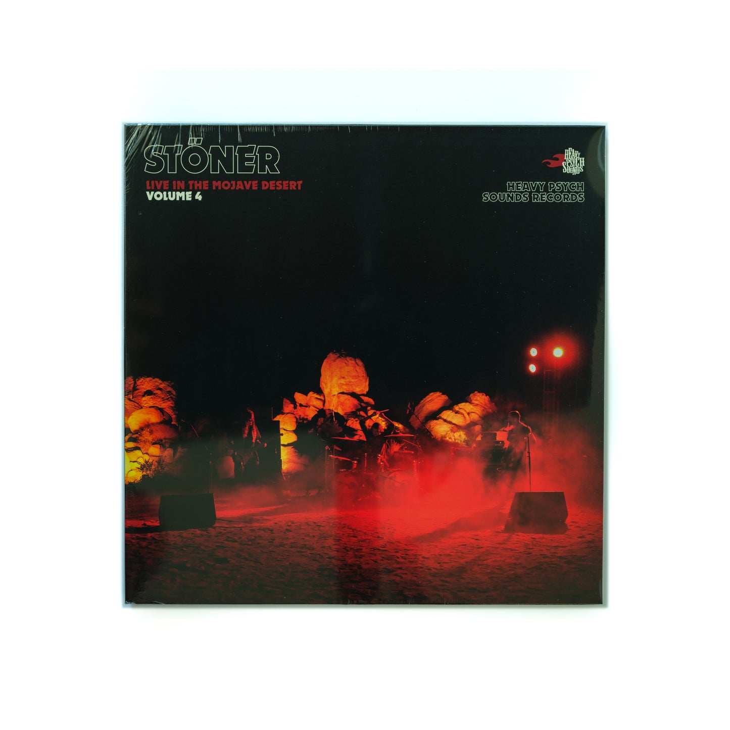 Front cover of Stöner – Live In The Mojave Desert Volume 4 vinyl LP, featuring a photo of the band playing in the desert at night surrounded by dust and the Stoner logo in bold. 