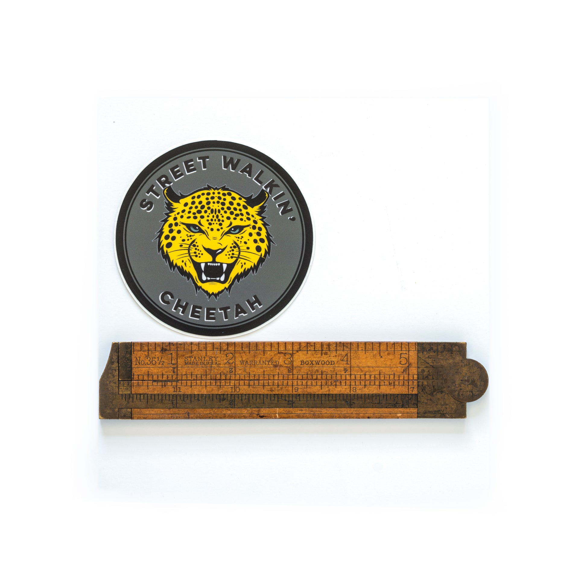 3.5-inch round black vinyl sticker featuring a cheetah in the center — inspired by The Stooges’ “Search and Destroy” lyric — matte, waterproof, and UV coated. Shot with a ruler to show scale. 