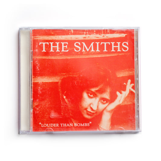 Front cover of The Smiths Louder Than Bombs CD featuring orange-toned photo of actress Shelagh Delaney, iconic 1987 compilation album cover, alternative rock music, 80s British band, Morrissey and Johnny Marr, Rough Trade Records release.