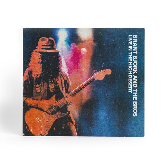 Album cover of Brant Bjork and the Bros Live in the High Desert feature a stylized photo of Brant playing guitar and text 'Brant Bjork and the Bros Live in the High Desert' on a blue background.