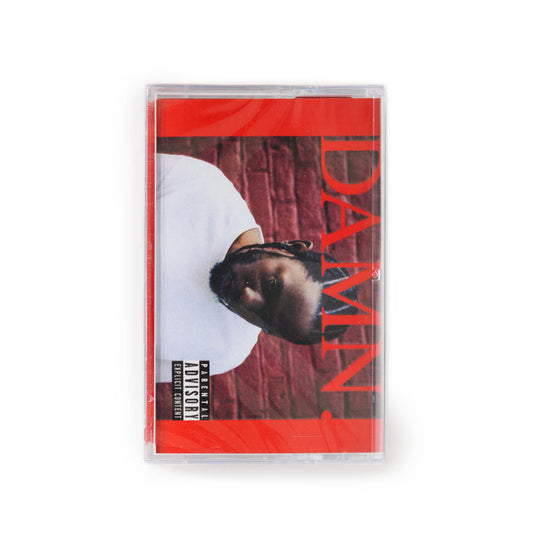 Front cover of fan import cassette of Kendrick Lamar Damn. Features a photo of the artist against a red brick wall with solid red bars on either side of him and DAMN. in bold red type. 