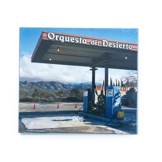 Orquesta Del Desierto – Dos CD front cover featuring a photo of an old gas station in the high desert of California; album title and band name displayed in subtle, modern typography that reflects the band’s fusion of desert rock, Latin, and ambient influences.