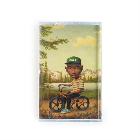Front cover of Tyler the Creator Wolf cassette tape. This version features a painting by Mark Ryden featuring Tyler sitting on a BMX bike near a lake in the woods, wearing a hat that says Wolf. 