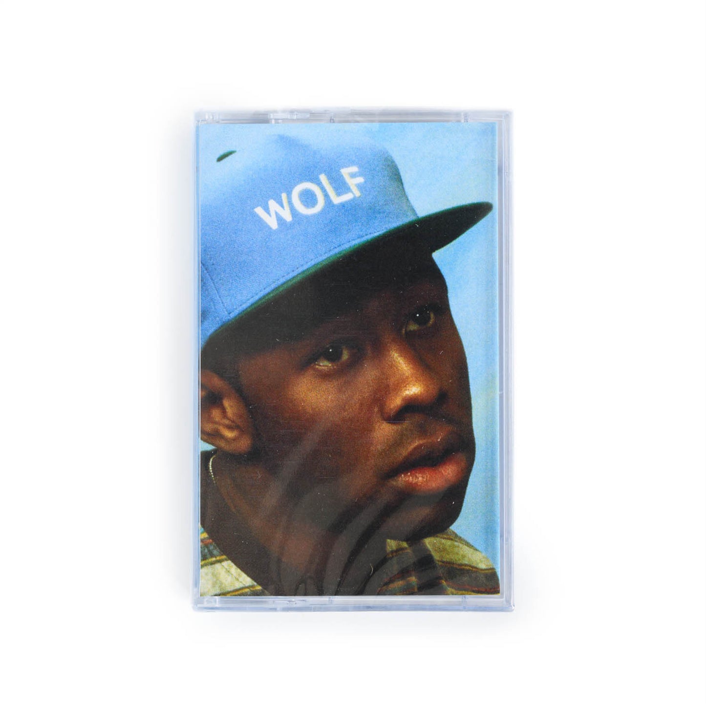 Front cover of Tyler The Creator Wolf cassette tape. This version features a portrait of Tyler against a blue background and wearing a blue hat with Wolf embroidered on the hat. 